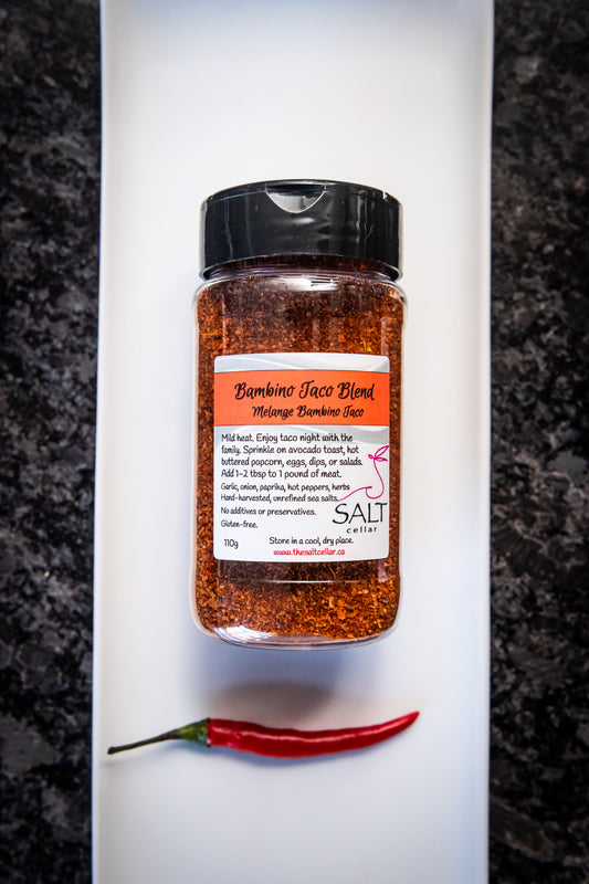 Bambino Taco Blend seasoning by The Salt Cellar displayed on a white plate with one fresh red chili pepper. This mild-heat spice blend, made with garlic, onion, paprika, and hot peppers, is perfect for tacos, avocado toast, popcorn, and more. Gluten-free, no additives, and handcrafted with unrefined sea salt.